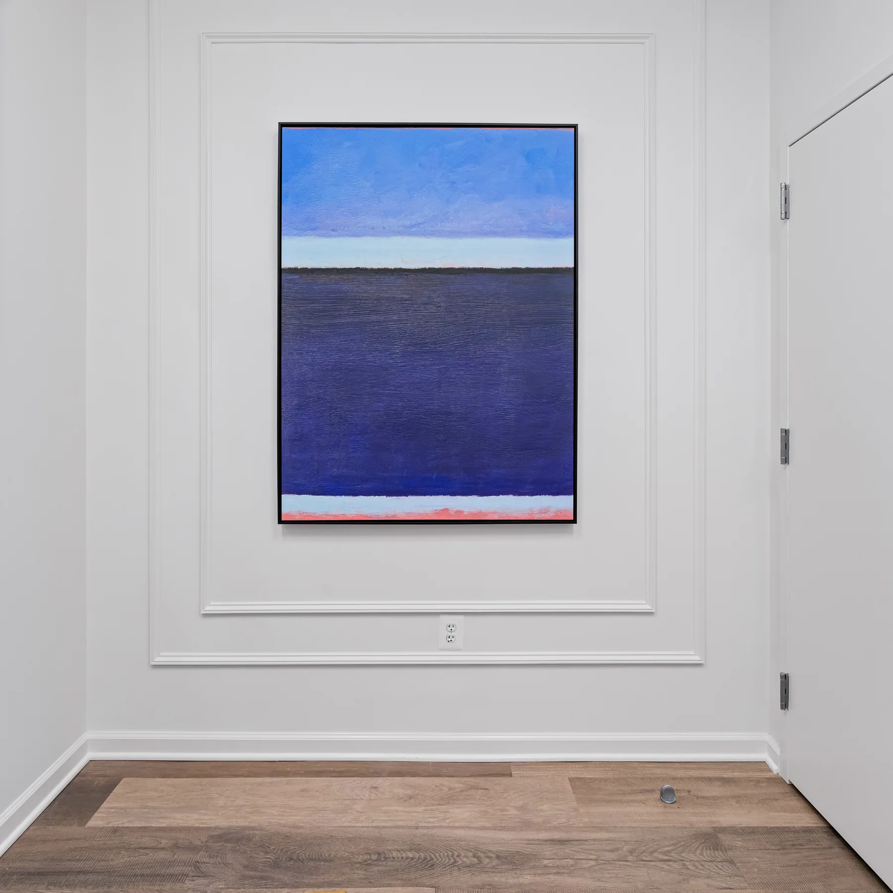 Blue abstract artwork centered within pale wall paneling.