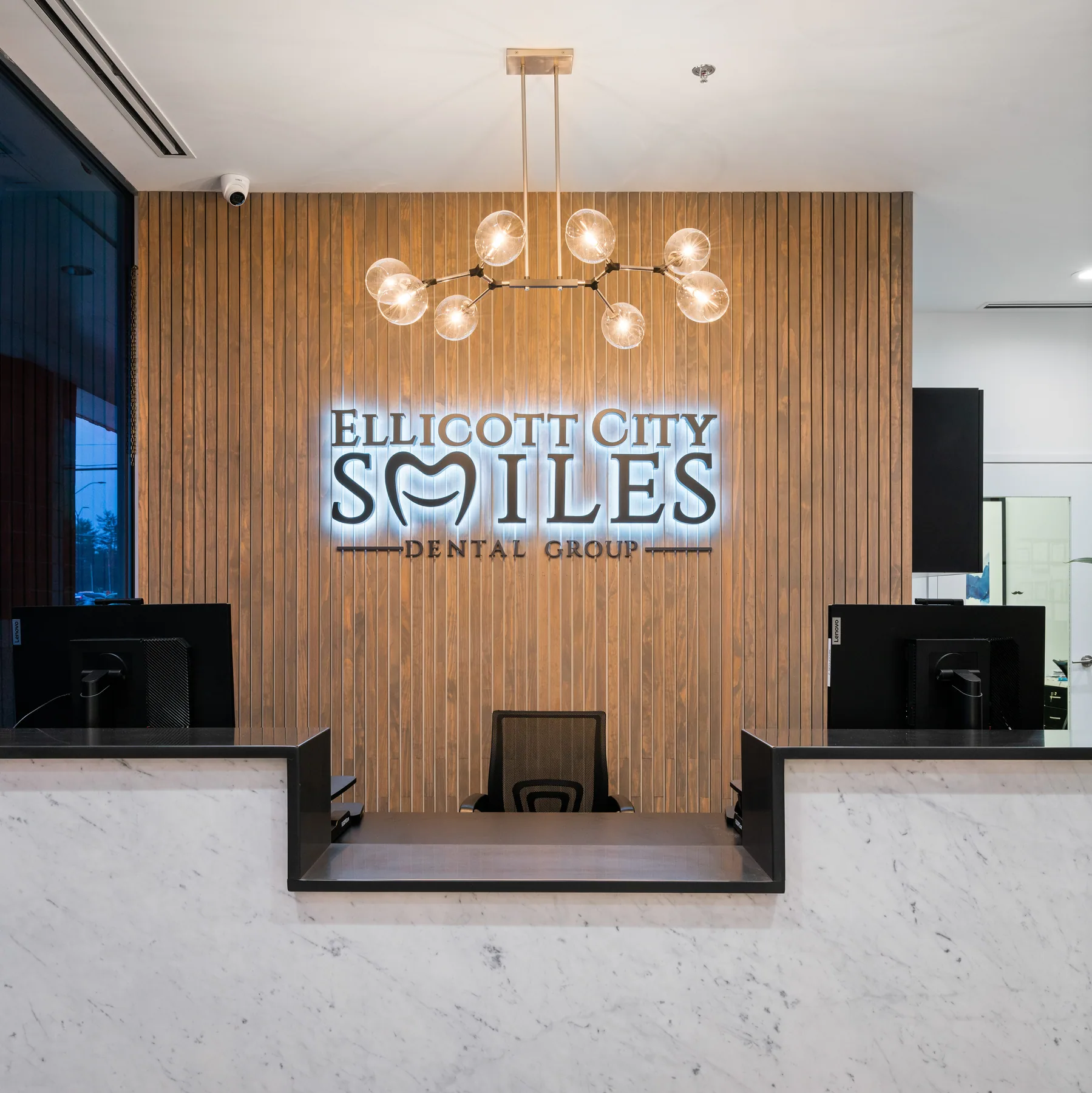 Pale reception counter, vertical timber wall and Ellicott City Smiles lettering.