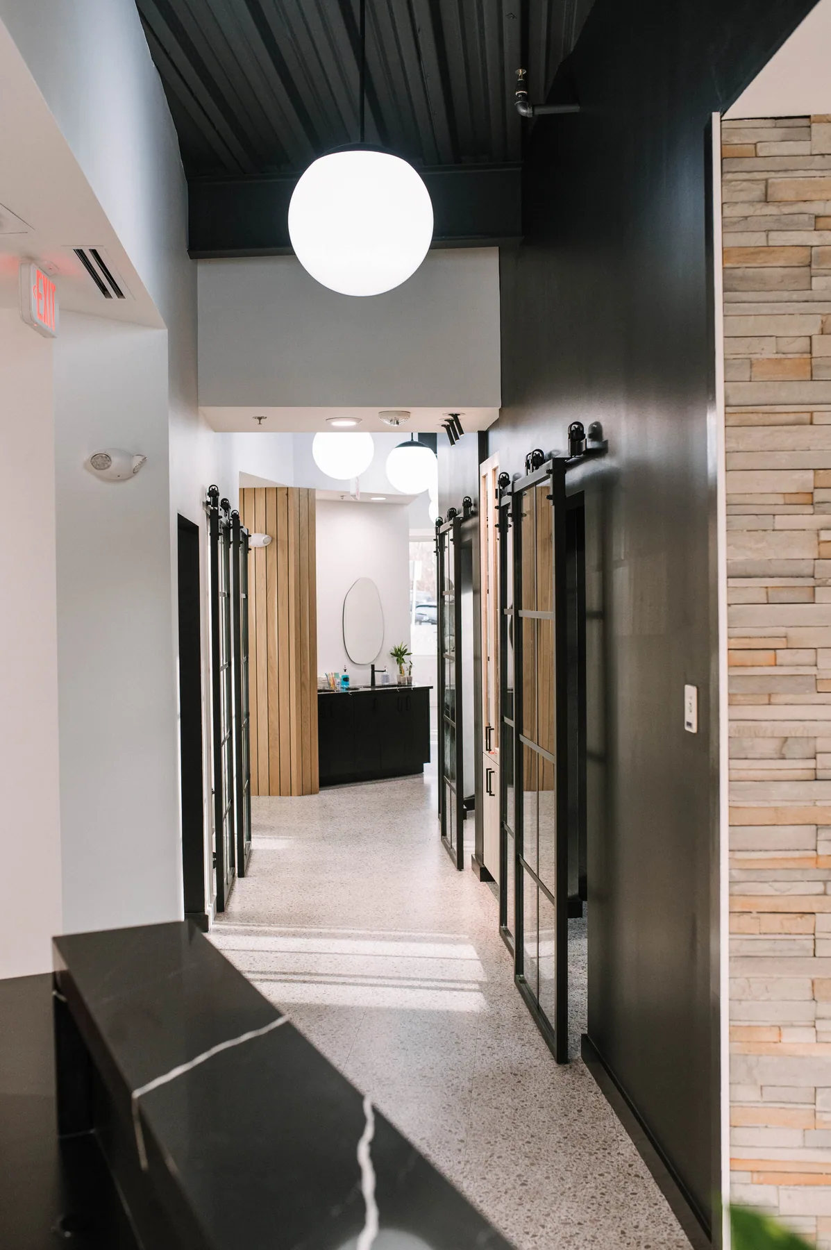 Long clinic corridor with dark ceiling and repeated globe pendants.