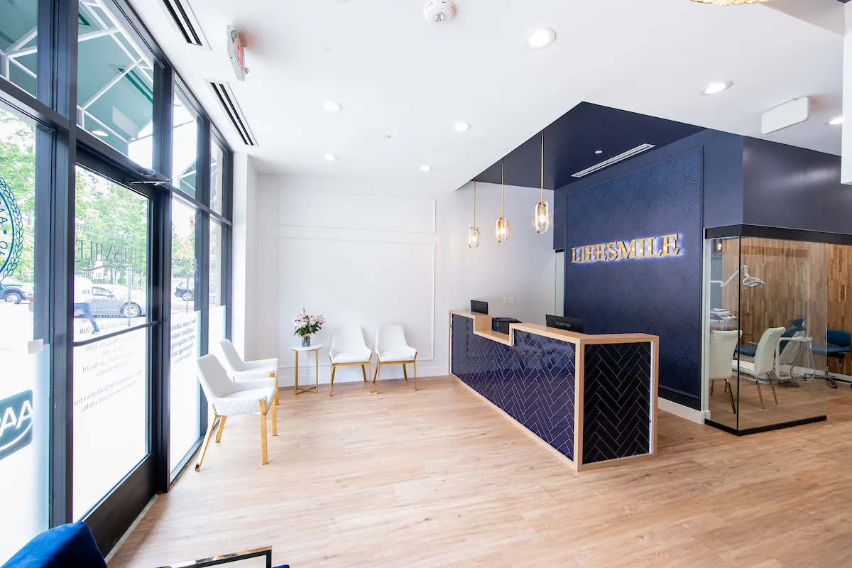Navy tiled reception desk beside full-height windows and white waiting chairs.