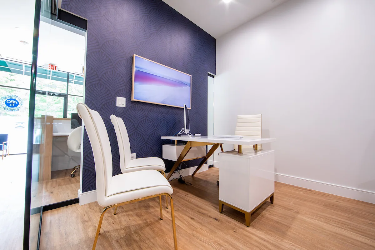 Consultation desk and white chairs against a textured navy wall.
