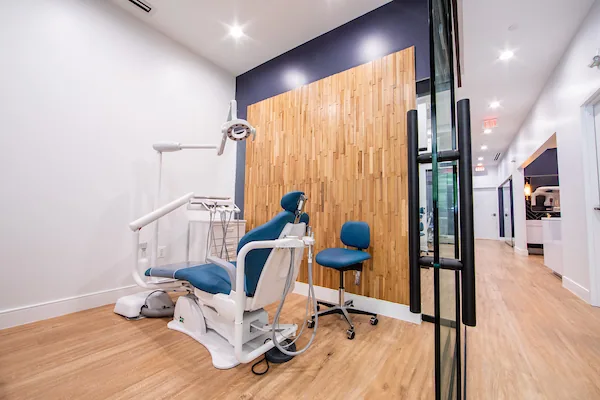 Dental treatment chair beside a timber feature wall and glazed partition.