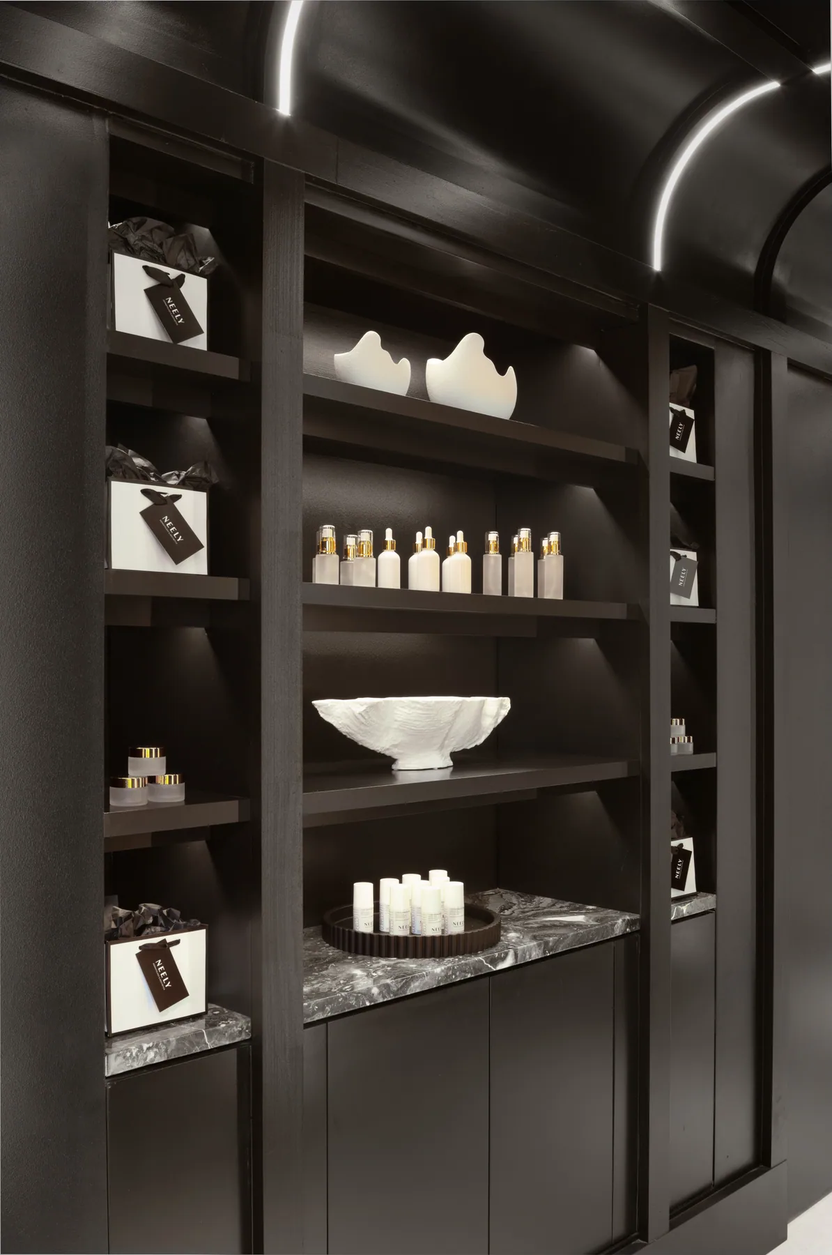 Arched retail/display shelving with products and decorative objects.