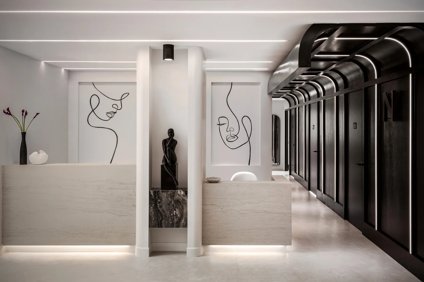 Reception counters beside a corridor with repeated curved ribs.