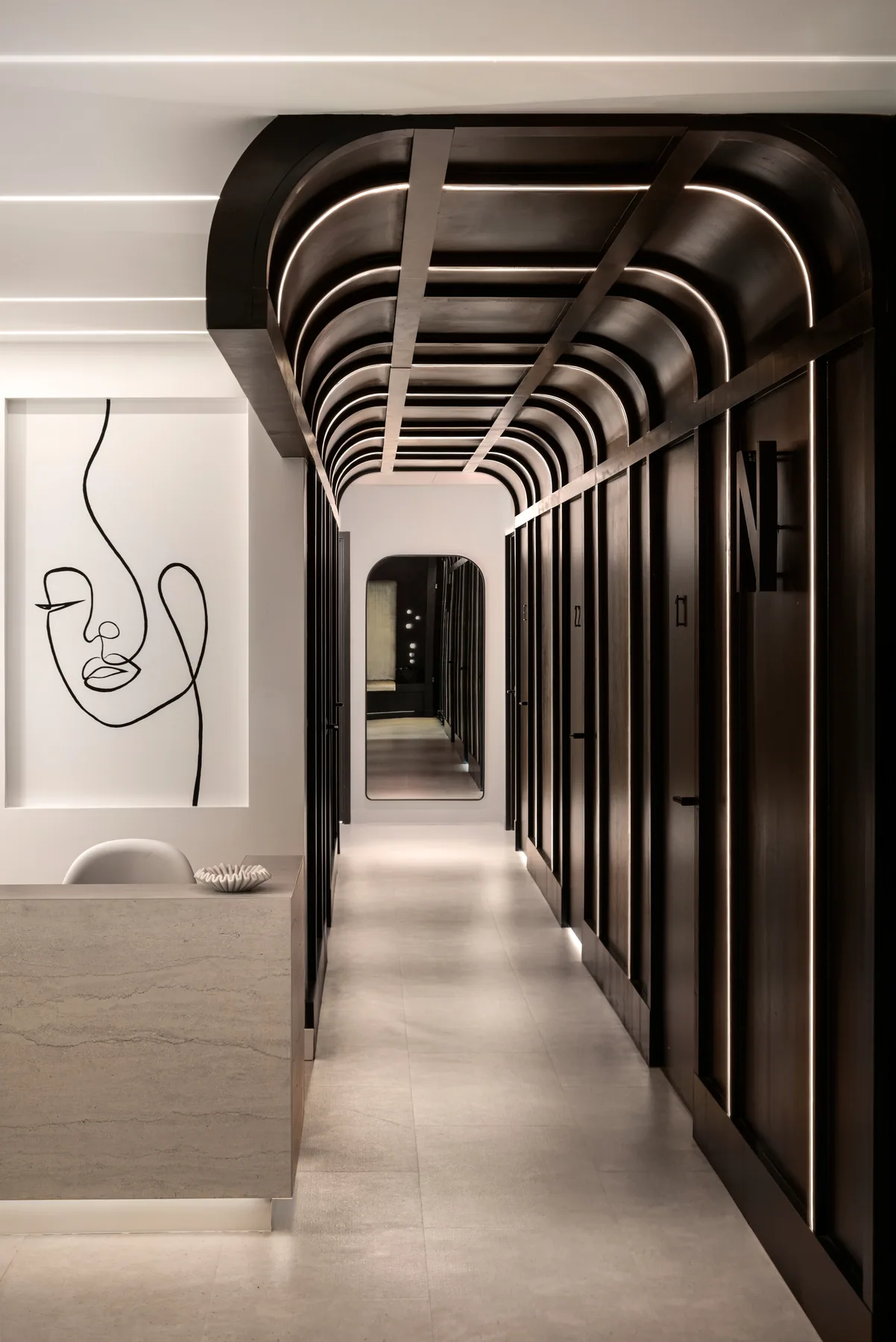 Long corridor photograph emphasizing curved dark ribs and linear lighting.